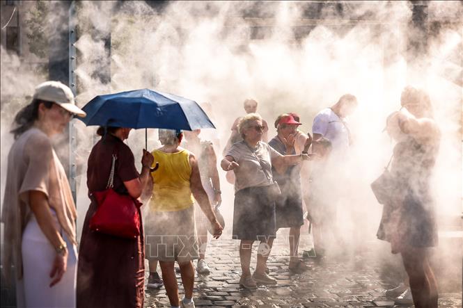 Người dân tránh nóng dưới hệ thống phun sương tại Budapest, Hungary. Ảnh: THX/TTXVN phát