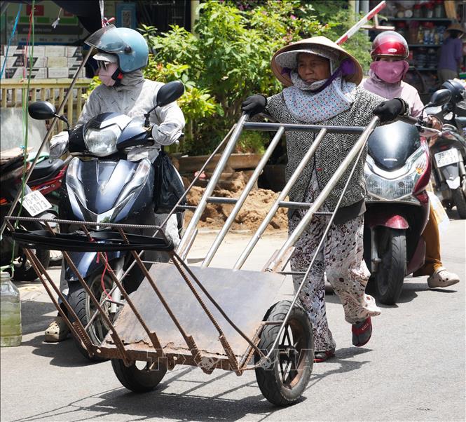 Vất vả di chuyển xe đẩy hàng hóa trên đường Chương Dương - chợ Đông Ba, thành phố Huế dưới trời nắng nóng. Ảnh: Nguyên Lý - TTXVN