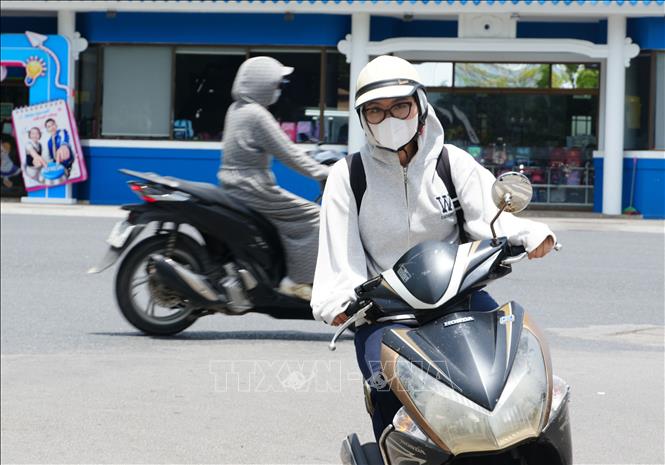 Người dân tham gia giao thông trên đường Trần Hưng Đạo, phường Phú Xuân, thành phố Huế, mặc đồ bảo hộ để giảm tác động nắng nóng. Ảnh: Nguyên Lý - TTXVN