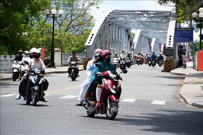 Người dân tham gia giao thông ở phía Bắc cầu Trường Tiền, thành phố Huế mặc đồ bảo hộ để giảm tác động nắng nóng. Ảnh: Nguyên Lý - TTXVN