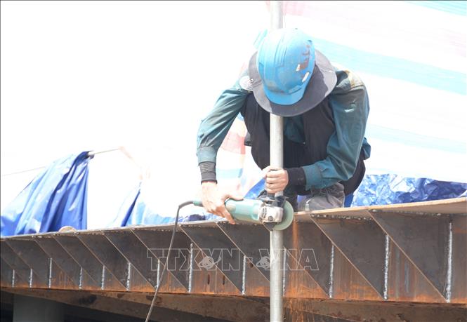 Công nhân trên công trường sửa chữa đập Thảo Long, thành phố Huế, đội thêm mũ rộng vành để giảm tác động nắng nóng. Ảnh: Nguyên Lý - TTXVN