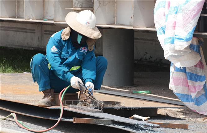 Công nhân trên công trường sửa chữa đập Thảo Long, thành phố Huế, đội thêm mũ rộng vành để giảm tác động nắng nóng. Ảnh: Nguyên Lý - TTXVN
