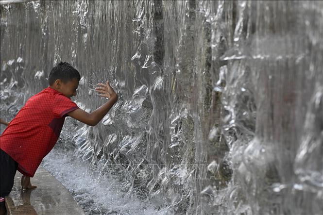 Em nhỏ tránh nóng bên đài phun nước tại Moskva, Nga. Ảnh: THX/TTXVN phát