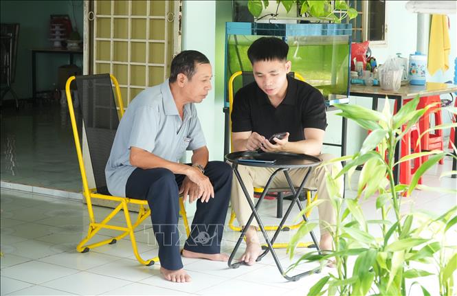 Các thành viên Tổ công nghệ số cộng đồng hướng dẫn người dân thực hiện dịch vụ công trực tuyến. Ảnh: Hữu Duyên - TTXVN