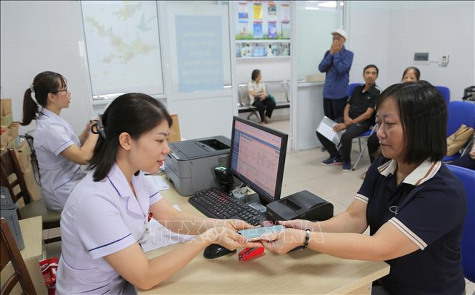 Người dân sử dụng điện thoại thông minh để xác nhận thông tin liên quan đến bảo hiểm tại Bệnh viện Hữu nghị Việt Tiệp. Ảnh: Minh Thu- TTXVN