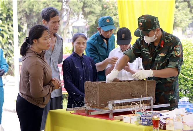 Người dân quan sát quá trình tổ lấy mẫu sinh phẩm hài cốt liệt sĩ tại Nghĩa trang Liệt sĩ Cao Đại, xã Vĩnh Thành. Ảnh: Hoàng Hùng - TTXVN