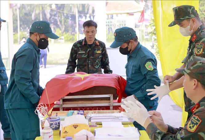 Dân phòng xã Vĩnh Thành đưa hài cốt liệt sĩ đã được phủ Quốc kỳ đến bàn lấy mẫu tại Nghĩa trang Liệt sĩ Cao Đại, xã Vĩnh Thành. Ảnh: Hoàng Hùng - TTXVN