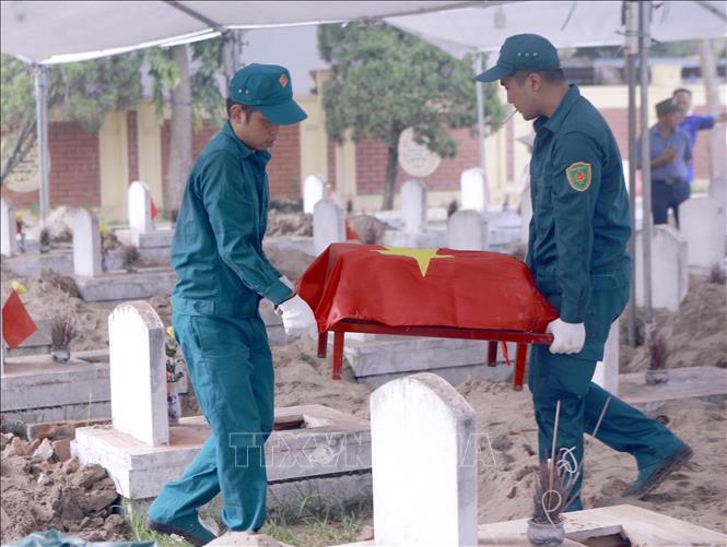 Tiểu đựng hài cốt liệt sĩ được đưa lên khỏi phần mộ để thực hiện lấy mẫu sinh phẩm tại Nghĩa trang Liệt sĩ Cao Đại, xã Vĩnh Thành. Ảnh: Hoàng Hùng - TTXVN