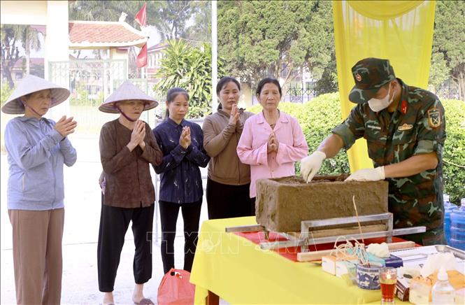 Người dân thành kính theo dõi quá trình tổ lấy mẫu sinh phẩm hài cốt liệt sĩ tại Nghĩa trang Liệt sĩ Cao Đại, xã Vĩnh Thành. Ảnh: Hoàng Hùng - TTXVN