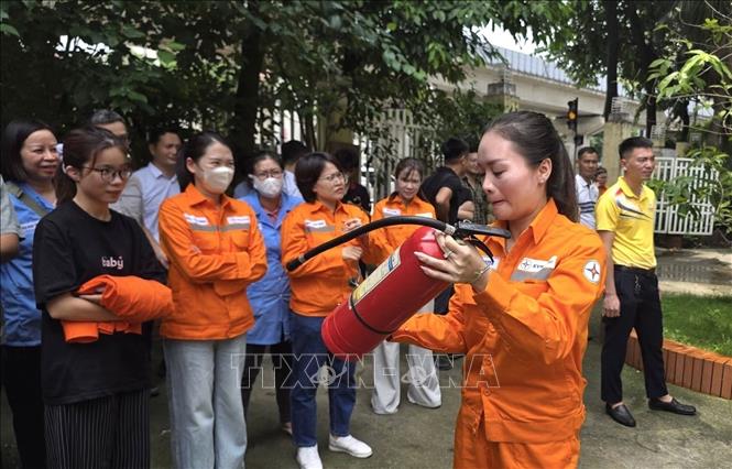 Cán bộ, công nhân ngành điện thực hành thao tác sử dụng bình chữa cháy xách tay dưới sự theo dõi của đồng nghiệp, qua đó nâng cao kỹ năng xử lý ban đầu khi xảy ra cháy, nổ. Ảnh: Quốc Lũy - TTXVN