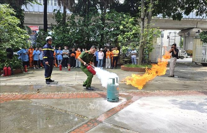 Lực lượng Công an thực hành sử dụng bình chữa cháy để dập tắt đám cháy giả định, hướng dẫn cán bộ, công nhân viên kỹ năng xử lý nhanh sự cố cháy, nổ ngay từ khi mới phát sinh. Ảnh: Quốc Lũy - TTXVN