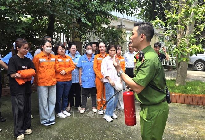 Lực lượng Công an hướng dẫn cán bộ, công nhân viên ngành điện cách sử dụng bình chữa cháy xách tay, giúp nâng cao kỹ năng xử lý ban đầu khi phát hiện sự cố cháy, nổ Ảnh: Quốc Lũy - TTXVN