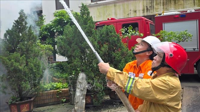 Công nhân ngành điện phối hợp với lực lượng phòng cháy, chữa cháy thực hành phun nước dập lửa trong tình huống giả định, góp phần nâng cao kỹ năng ứng phó và xử lý sự cố cháy, nổ tại đơn vị. Ảnh: Quốc Lũy - TTXVN
