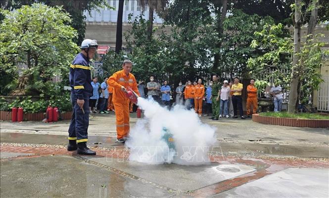 Công nhân ngành điện thực hành sử dụng bình chữa cháy xách tay để xử lý tình huống cháy giả định dưới sự hướng dẫn, giám sát của lực lượng phòng cháy, chữa cháy. Ảnh: Quốc Lũy - TTXVN