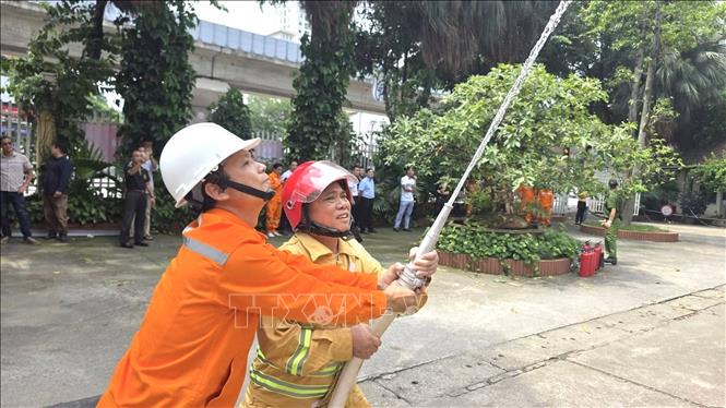 Cán bộ, công nhân ngành điện thực hành kỹ năng sử dụng vòi chữa cháy trong tình huống giả định, nâng cao khả năng phối hợp và xử lý sự cố cháy, nổ tại đơn vị. Ảnh: Quốc Lũy - TTXVN