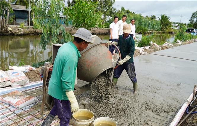 Thi công công trình đường giao thông nông thôn dọc kênh Ô Môi, xã Vĩnh Bình. Ảnh: Văn Sĩ - TTXVN                                 