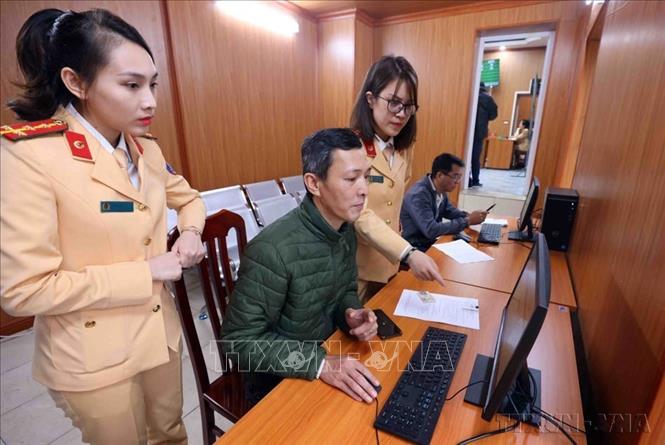 Cán bộ, chiến sĩ Đội Sát hạch, cấp giấy phép lái xe cơ giới đường bộ (Phòng CSGT, Công an TP Hà Nội) hướng dẫn người dân làm thủ tục đăng ký cấp, đổi giấy phép lái xe trên Cổng dịch vụ công quốc gia và ứng dụng VNeID (01/03/2025). Ảnh: Phạm Kiên - TTXVN