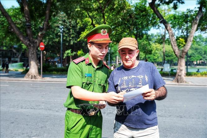 Cán bộ Công an giới thiệu cho một du khách nước ngoài tìm hiểu thông tin về Kiosk “Trạm Cảnh sát thông minh”, góp phần giúp người nước ngoài tiếp cận thuận tiện hơn với các dịch vụ hỗ trợ của lực lượng Công an. Ảnh: Phạm Tuấn Anh - TTXVN