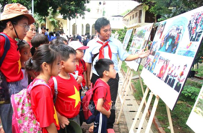 Các em nhỏ say mê lắng nghe câu chuyện qua ảnh về các chiến sĩ ngày đêm canh giữ biển đảo quê hương. Ảnh: Hương Giang - TTXVN
