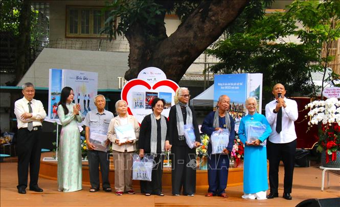 Nghệ sĩ Nhiếp ảnh Nguyễn Á tặng sách cho các cô, chú từng là cựu tù Côn Đảo. Ảnh: Hương Giang - TTXVN