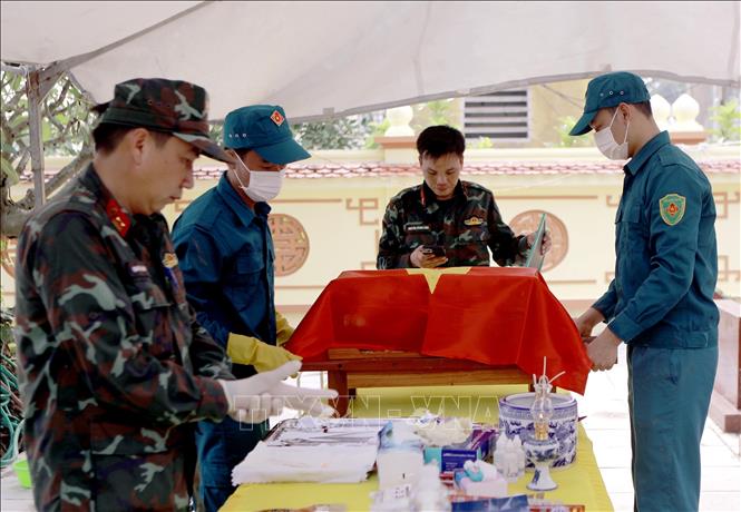Lực lượng chức năng di chuyển tiểu sành chứa hài cốt liệt sĩ chưa xác định được thông tin đến khu vực lấy mẫu tại Nghĩa trang liệt sĩ Hợp Lý, xã Hợp Lý. Ảnh: Hoàng Hùng - TTXVN
