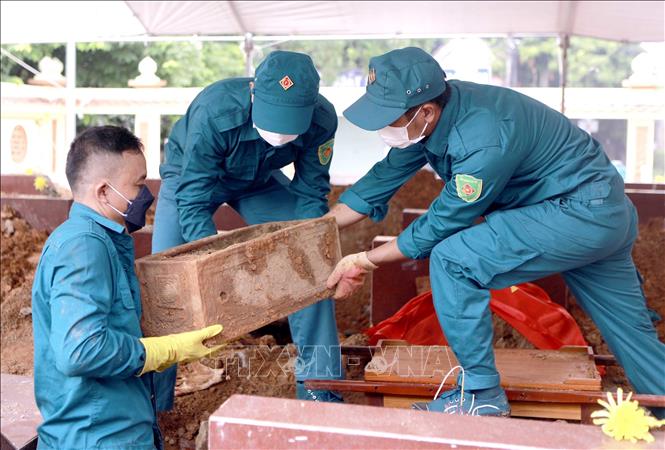 Lực lượng chức năng di chuyển tiểu sành chứa hài cốt liệt sĩ chưa xác định được thông tin tới khu vực lấy mẫu tại Nghĩa trang liệt sĩ Hợp Lý, xã Hợp Lý. Ảnh: Hoàng Hùng - TTXVN