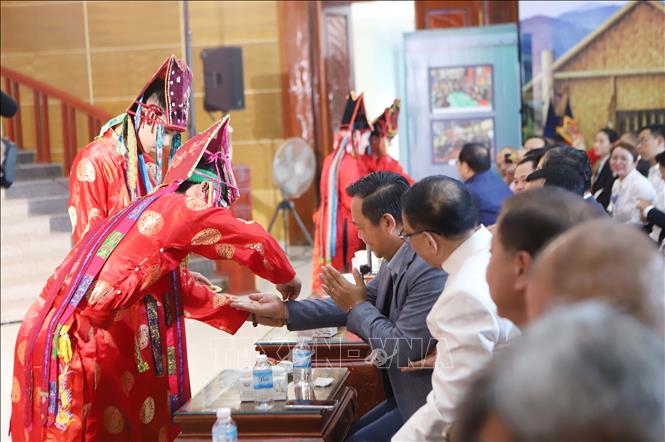 Các nghệ nhân buộc chỉ cổ tay cầu chúc may mắn cho các đại biểu phía Lào tham dự sự kiện. Ảnh: Xuân Tú - PV TTXVN tại Lào