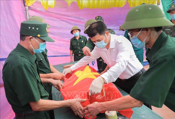 Thực hiện nghi thức phủ Quốc kỳ trang trọng, tri ân Anh hùng liệt sĩ đã hy sinh vì độc lập, tự do của Tổ quốc tại Nghĩa trang trang liệt sĩ Liên Hiệp (xã Hát Môn). Ảnh: Phan Phương - TTXVN