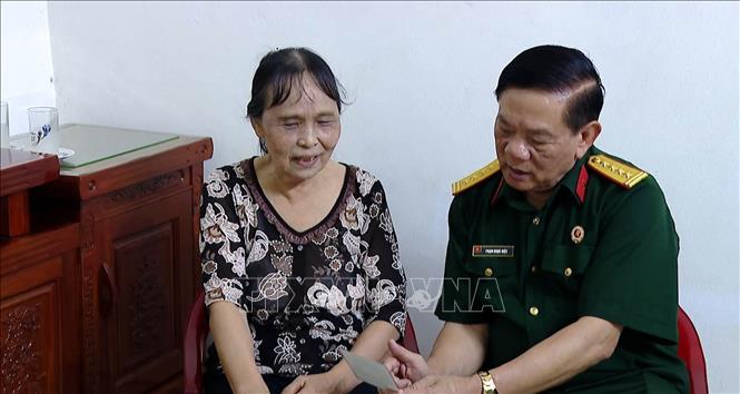 Bà Trần Thị Gấm (vợ liệt sĩ Vũ Văn Thành, quê Nam Định) chia sẻ những kỷ vật chiến trường của chồng với Đại tá Phạm Ngọc Hiệu, mong ước đưa hài cốt liệt sĩ hồi hương được vẹn tròn. Ảnh: Hải Yến - TTXVN