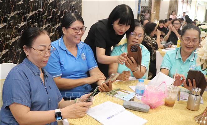 Đại diện Hội Liên hiệp phụ nữ thành phố hỗ trợ học viên thực hành ứng dụng AI trên điện thoại. Ảnh: Nguyễn Hằng - TTXVN