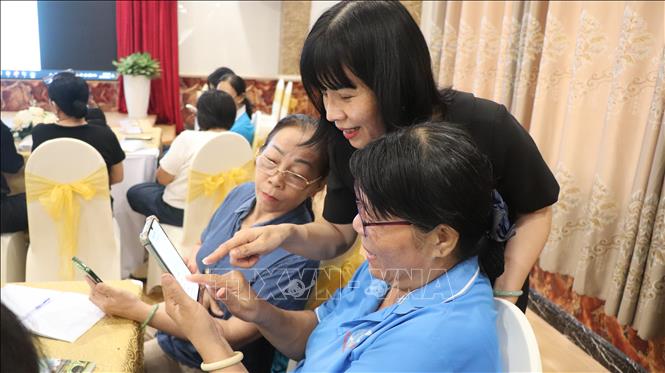 Đại diện Hội Liên hiệp phụ nữ thành phố hỗ trợ học viên thực hành ứng dụng AI trên điện thoại. Ảnh: Nguyễn Hằng - TTXVN