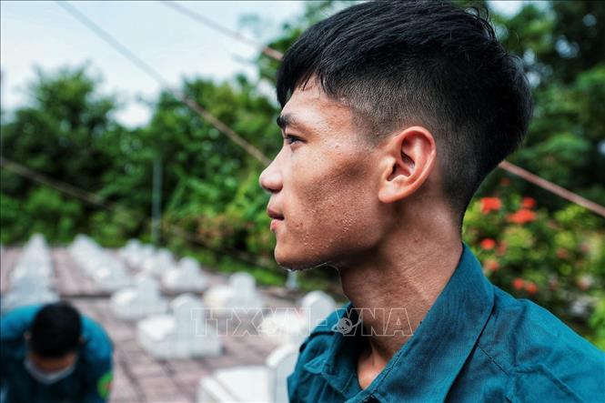 Mồ hôi trên gương mặt một chiến sĩ dân quân tự vệ trong quá trình mở phần mộ liệt sĩ. Giữa thời tiết nắng nóng, các lực lượng vẫn miệt mài thực hiện từng công đoạn với sự cẩn trọng, trách nhiệm, nỗ lực hoàn thành nhiệm vụ lấy mẫu hài cốt phục vụ giám định ADN. Ảnh: Phạm Tuấn Anh - TTXVN