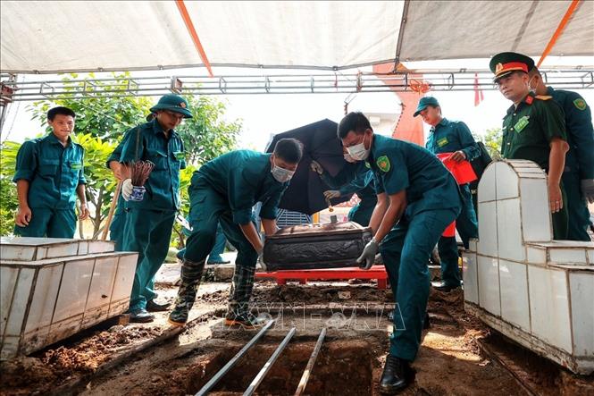 Lực lượng dân quân tự vệ cẩn trọng đưa phần chứa hài cốt liệt sĩ trở lại vị trí an táng sau khi đã thực hiện công đoạn lấy mẫu ADN. Ảnh: Phạm Tuấn Anh - TTXVN