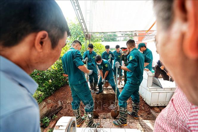 Lực lượng dân quân tự vệ tiến hành đào mở phần mộ liệt sĩ chưa xác định được thông tin tại Nghĩa trang Liệt sĩ Minh Phú để tiếp cận hài cốt, phục vụ công tác lấy mẫu giám định ADN. Ảnh: Phạm Tuấn Anh - TTXVN