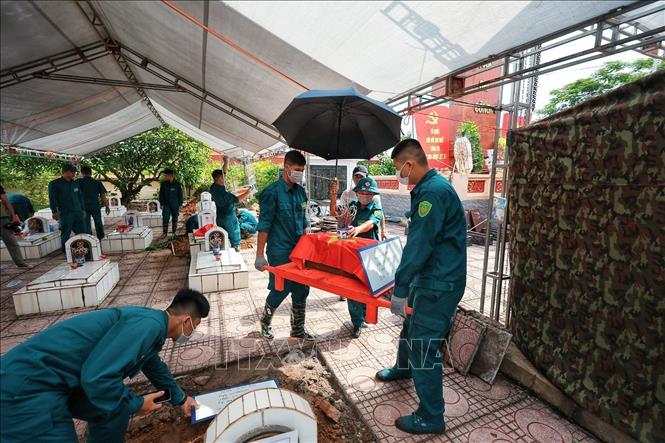 Hài cốt liệt sĩ khi được đưa lên khỏi vị trí an táng được phủ Quốc kỳ và cẩn trọng chuyển tới khu vực chuyên môn để thực hiện các bước lấy mẫu phục vụ giám định ADN. Ảnh: Phạm Tuấn Anh - TTXVN