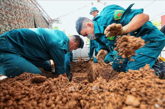 Các thành viên tổ công tác trực tiếp dùng tay bóc tách từng lớp đất quanh phần quách, thao tác cẩn trọng nhằm hạn chế tác động đến quách trước khi thực hiện lấy mẫu giám định ADN. Ảnh: Phạm Tuấn Anh - TTXVN