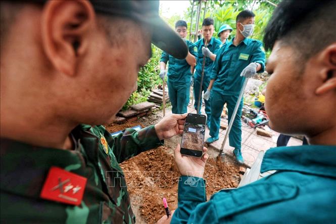 Các thành viên tổ công tác ghi nhận bằng hình ảnh phục vụ công tác số hoá hiện trạng phần mộ trước khi tiến hành mở mộ, lấy mẫu hài cốt liệt sĩ phục vụ giám định ADN. Ảnh: Phạm Tuấn Anh - TTXVN