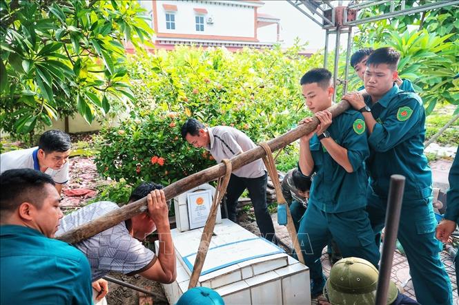 Lực lượng dân quân tự vệ tháo dỡ các cấu kiện phía trên phần mộ liệt sĩ chưa xác định được thông tin để phục vụ công tác lấy mẫu hài cốt giám định ADN tại Nghĩa trang Liệt sĩ Minh Phú, xã Kim Anh, thành phố Hà Nội. Ảnh: Phạm Tuấn Anh - TTXVN