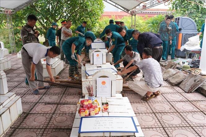 Lực lượng chức năng thực hiện lấy mẫu hài cốt liệt sĩ tại Nghĩa trang liệt sĩ Minh Phú, xã Kim Anh. Ảnh: Quốc Lũy - TTXVN