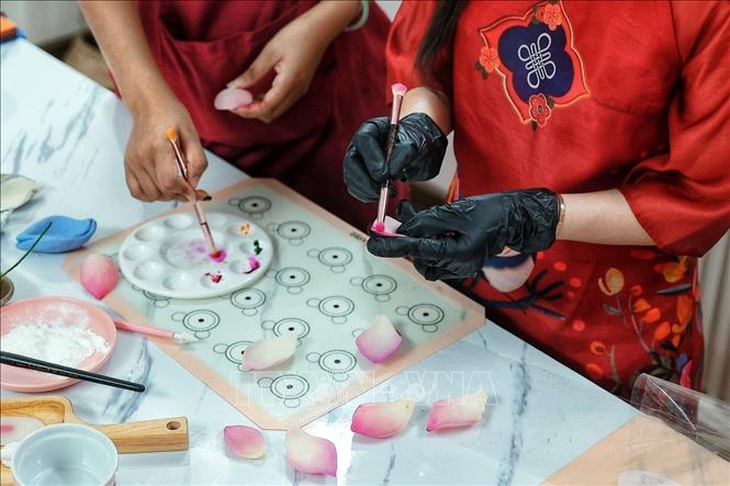 The artisans use food coloring to tint the *tò he* (traditional dough figurine) paste, adding definition and realistic hues to the flower petals. VNA Photo: Phạm Tuấn Anh
