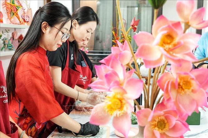 The shaping process is carried out entirely by hand, requiring meticulous attention to detail to ensure that the petals, stamens, buds, and stems—crafted from *to he* dough—come together to form a natural and harmonious whole. VNA Photo: Phạm Tuấn Anh
