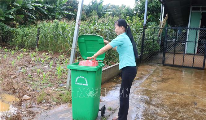 Chị Lê Thị Ngọc Diệp, người dân thôn Thống Nhất, xã Đak Nhau, thực hiện bỏ rác đúng nơi quy định, góp phần giữ gìn vệ sinh môi trường khu dân cư. Ảnh: Đậu Tất Thành - TTXVN