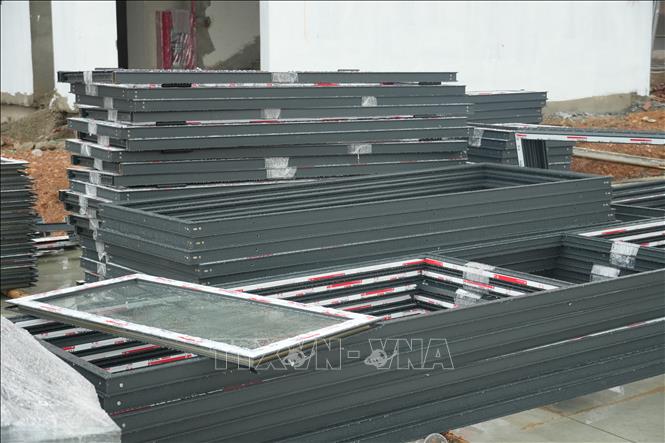 Hệ thống khung cửa chính, cửa sổ phòng học tại Trường Phổ thông nội trú liên cấp Tiểu học và Trung học cơ sở Anh Sơn, xã Anh Sơn được các nhà thầu tập kết tại sân trường và hoàn thiện lắp ráp hoàn chỉnh các phòng học còn lại vào cuối tuần này. Ảnh: Bích Huệ - TTXVN