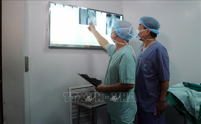 Các bác sỹ kiểm tra phim chụp trước khi phẫu thuật. Ảnh: Nguyễn Chinh - TTXVN