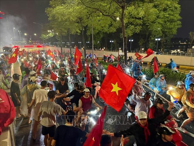 Niềm vui sau chiến thắng khiến người hâm mộ Thủ đô dù mưa vẫn ra đường chung vui cùng đội tuyển Việt Nam. Ảnh: Minh Quyết - TTXVN