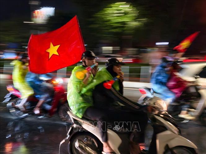 Niềm vui sau chiến thắng khiến người hâm mộ Thủ đô dù mưa vẫn ra đường chung vui cùng đội tuyển Việt Nam. Ảnh: Minh Quyết - TTXVN