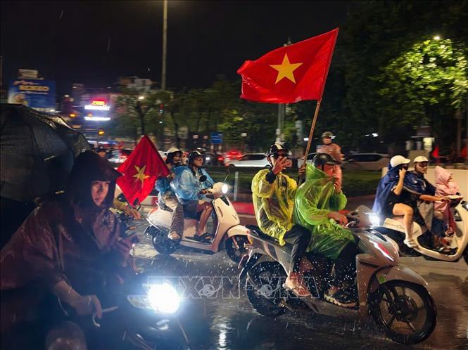 Niềm vui sau chiến thắng khiến người hâm mộ Thủ đô dù mưa vẫn ra đường chung vui cùng đội tuyển Việt Nam. Ảnh: Minh Quyết - TTXVN