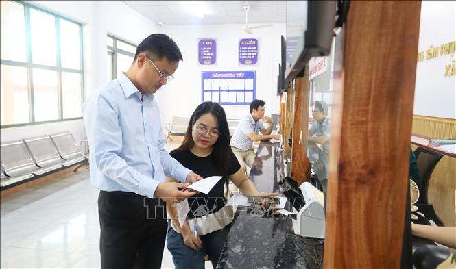 Bí thư xã Đak Nhau Nguyễn Trọng Lâm nắm tình hình, trao đổi với người dân tại bộ phận tiếp nhận và giải quyết thủ tục hành chính. Ảnh: Đậu Tất Thành – TTXVN.