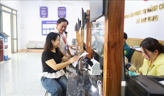 Chủ tịch UBND xã Đăk Nhau Tô Hoài Nam thăm hỏi, hướng dẫn người dân thực hiện thủ tục hành chính tại Trung tâm Phục vụ hành chính công xã. Ảnh: Đậu Tất Thành – TTXVN.