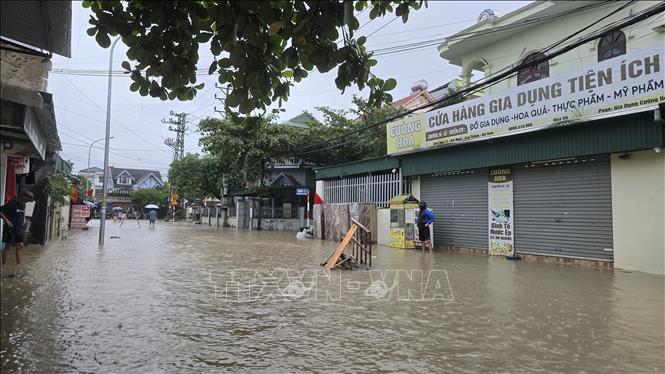 Nước ngập cao lên cao, người dân phải mang các vật dụng để trước nhà chặn xe ô tô đi qua gây tràn nước vào nhà. Ảnh: Thanh Vân - TTXVN